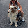 animal, blue_eyes, casual_clothing, companion, crouching, daylight, dog, friendship, grass, leash, long_hair, nature, outdoor, pavement, pet, road, smiling, summer, walking, woman