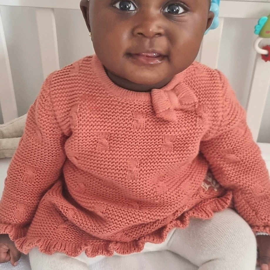 Queenstar is registered to the contest to win money with this photo: accessories, baby, cap, clothing, dress, face, happy, hat, head, hosiery, knitwear, pants, person, photography, portrait, sitting, sleeve, smile, sock, sweater