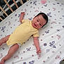 baby, bed_sheet, butterfly_pattern, child, crib, cute, flower_pattern, happy, indoor, infant, lying_down, newborn, nursery, pacifier, person, resting, smiling, toddler, wooden_crib, yellow_onesie