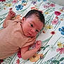 baby, newborn, infant, lying_down, striped_clothing, floral_pattern, bed_sheet, curious, fists, face, head, skin, person, indoors, cute, small, resting, soft_light, sleepwear, child