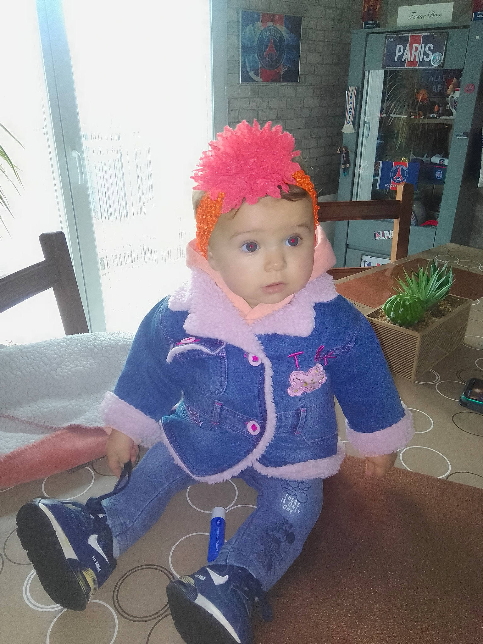Eva a rejoint le concours — aidez-le/la à gagner de superbes lots ! baby, baby_toddler_clothing, beanie, camera, cap, child, costume, fashion_accessory, flooring, flowerpot, fun, hat, headwear, houseplant, magenta, person, plant, room, sitting, toddler