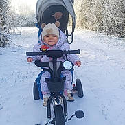 Shaïna a rejoint le concours — aidez-le/la à gagner de superbes lots ! child, toddler, tricycle, stroller, snow, winter, beanie, hat, coat, boots, smile, outdoors, path, trees, parent, handlebars, mirror, bundled_up, cold, playtime