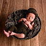 Bakari is registered to the contest to win money with this photo: baby, basket, child, cozy, cute, feet, hands, hat, indoors, infant, knitted_outfit, newborn, peaceful, portrait, resting, sleeping, soft_texture, warm_lighting, wooden_floor, wool