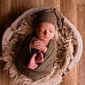 baby, basket, blanket, cozy, cute, hands_together, hat, indoors, infant, knit, newborn, peaceful, portrait, resting, sleeping, soft_texture, tiny_feet, warm, wooden_floor, wrapped