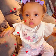 Tihira joined the competition — help win amazing prizes! baby, child, pajamas, bib, purple_bows, couch, indoor, heart_graphics, cute, infant, sitting, clothing, person, adorable, young_child, pink, soft_lighting, expression, portrait, home