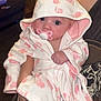 baby, infant, pacifier, hooded_robe, pink, white, animal_print, person, arms, indoor, carpet, furniture, table, photo_frame, blanket, cute, child, young, portrait, clothing
