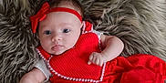 Elaina is registered to the contest to win money with this photo: baby, infant, red_dress, headband, fluffy_rug, lying_down, cute, small_hands, blue_eyes, curious_expression, soft_texture, indoors, portrait, child, adorable, clothing, closeup, person, young, face