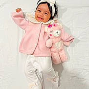 Devika is registered to the contest to win money with this photo: adorable, baby, bow, child, clothing, cute, happy, headband, indoor, infant, lying_down, person, pink_jacket, plush_toy, portrait, smiling, soft_toy, teddy_bear, white_background, white_pants