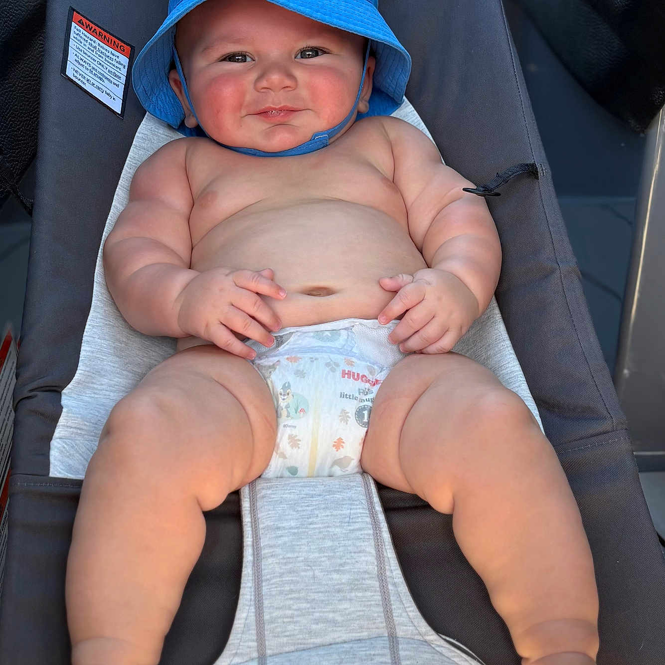 Stetson is registered to the contest to win money with this photo: baby, baby_seat, blue_hat, child, chubby, cute, diaper, face, feet, hands, happy, infant, legs, outdoor, relaxing, rosy_cheeks, skin, smiling, sunhat, sunlight