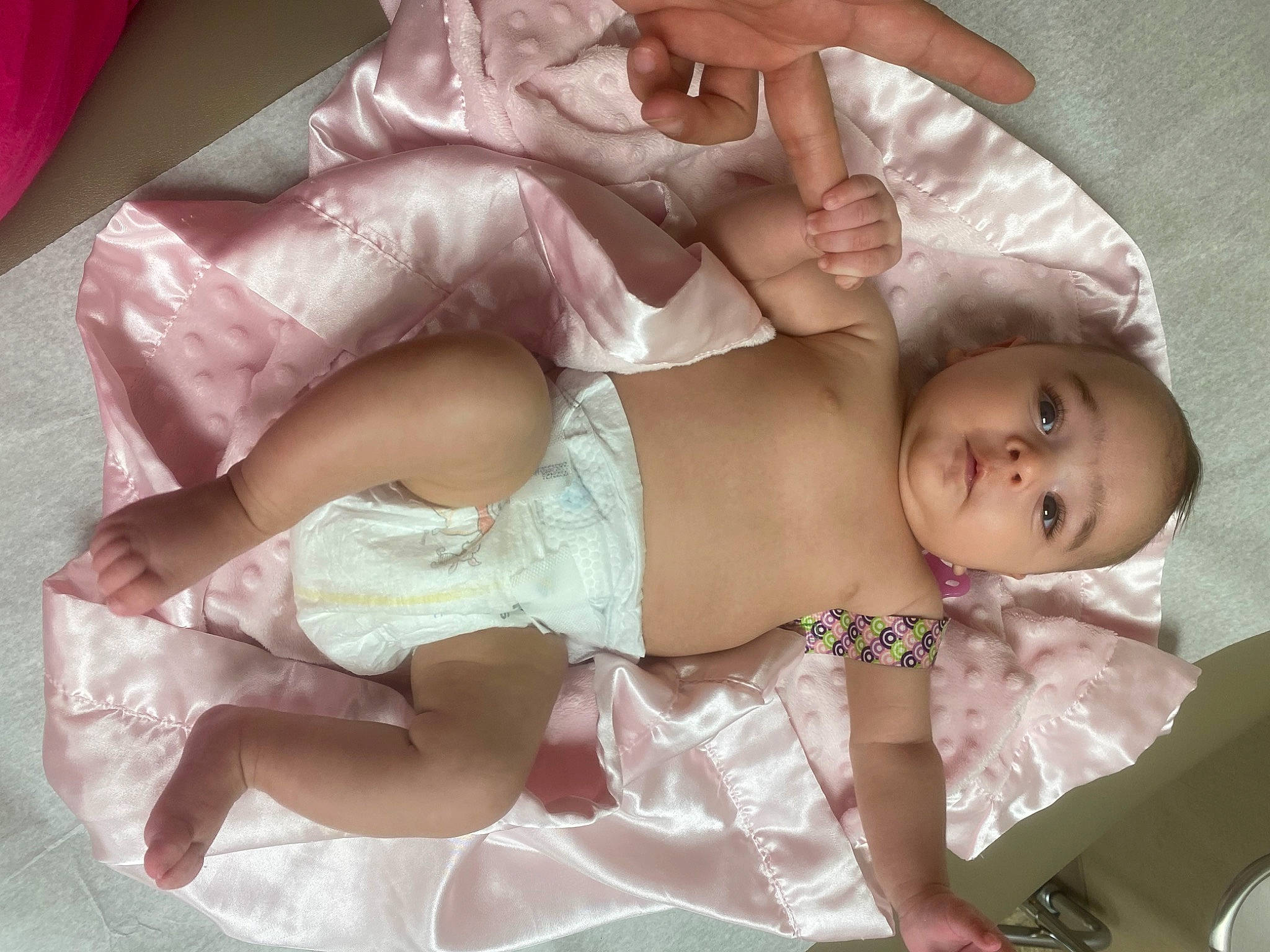 Leah is registered to the contest to win money with this photo: baby, baby_toddler_clothing, cheek, chest, child, comfort, dress, embellishment, fashion_accessory, foot, hair_accessory, headgear, headpiece, human_leg, lap, mouth, person, pink, skin, thigh