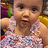 child, toddler, girl, portrait, face, smiling, wide_eyed, bow, dress, pink, floral, ruffles, indoor, party, balloons, colorful, sitting, curly_hair, baby, photography