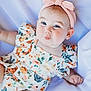 Jemma is registered to the contest to win money with this photo: adorable, baby, baby_clothes, blue_eyes, child, chubby_cheeks, closeup, cute, cute_expression, floral_outfit, headband, infant, infant_girl, lying_down, portrait, pouting, skin, smiling, soft_background, white_fabric