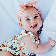Jemma joined the competition — help win amazing prizes! arm, baby, blue_eyes, cheerful, child, closeup, cute, face, floral_dress, happy, headband, indoors, infant, person, pink, portrait, skin, smile, soft, white_background
