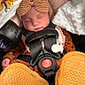 baby, sleeping, car_seat, headband, bow, blanket, clothing, footwear, child, infant, safety_harness, fan, soft_texture, closeup, indoors, cute, peaceful, warm_colors, resting, newborn