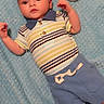James is registered to the contest to win money with this photo: baby, infant, blue_blanket, striped_shirt, blue_shorts, lion_plush, toy_story, woody_character, soft_texture, cute, child, lying_down, indoors, playful, clothing, sock, portrait, adorable, young_child, comfortable