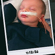 James is registered to the contest to win money with this photo: baby, sleeping, nasal_tube, polaroid, handwritten_date, infant, face, closed_eyes, hospital, medical_tape, child, portrait, clothing, skin, head, resting, newborn, person, indoor, cute