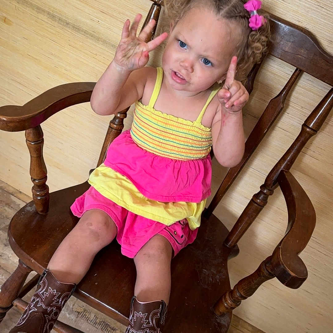Zoey joined the competition — help win amazing prizes! brown_boots, casual_clothing, child, counting, curly_hair, expression, flooring, girl, hands_up, home_interior, indoor, person, pink_bows, pink_skirt, portrait, sitting, toddler, wooden_chair, wooden_floor, yellow_top