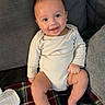 baby, smiling, infant, sitting, blanket, plaid, couch, gray, happy, cute, child, indoors, face, skin, foot, hand, onesie, cozy, comfort, young