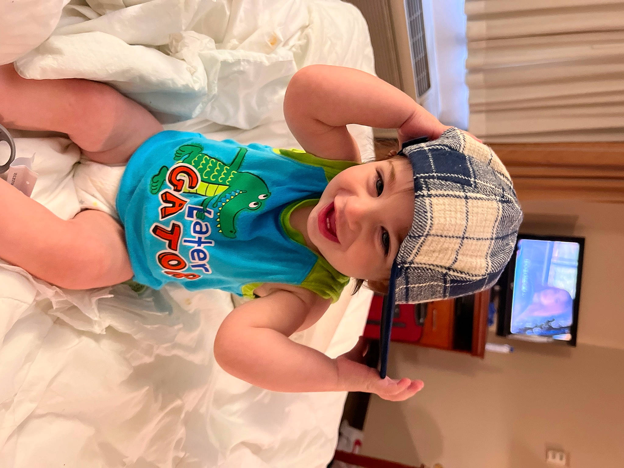 Grayson is registered to the contest to win money with this photo: baby, baby_toddler_clothing, blurred, child, comfort, elbow, finger, fun, happy, hat, headwear, joy, leg, pattern, person, sleeve, smile, t_shirt, television, textile