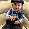 Kyson is registered to the contest to win money with this photo: toddler, child, boy, smiling, hat, bow_tie, suspenders, shirt, pants, chair, indoor, portrait, cute, happy, fashion, baby, person, seated, casual, closeup