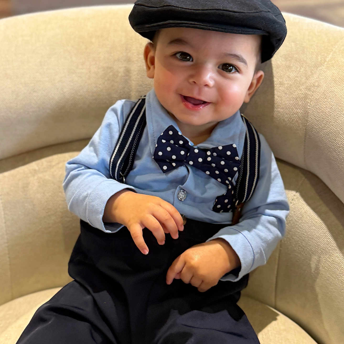 Kyson is registered to the contest to win money with this photo: toddler, child, boy, smiling, hat, bow_tie, suspenders, shirt, pants, chair, indoor, portrait, cute, happy, fashion, baby, person, seated, casual, closeup
