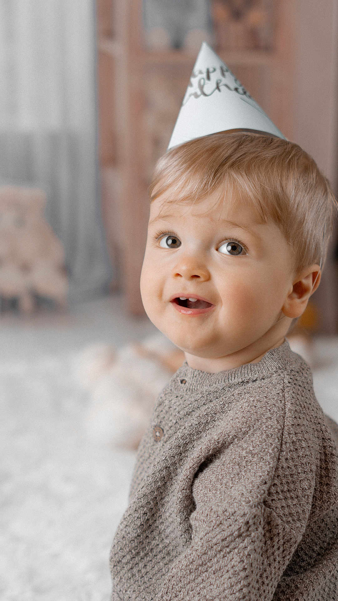 Stefan a rejoint le concours — aidez-le/la à gagner de superbes lots ! child, toddler, portrait, party_hat, hat, sweater, cute, smiling, face, eyes, blond_hair, indoor, close_up, soft_lighting, nursery, plush_toy, carpet, celebration, candid, baby