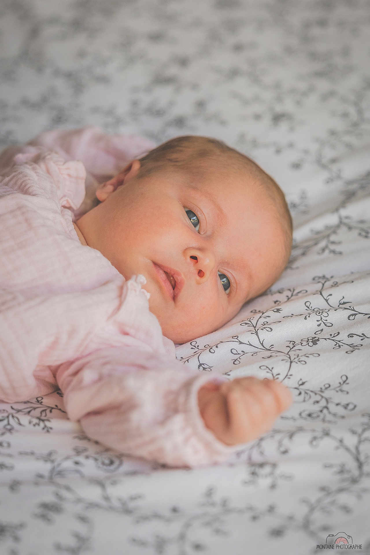 Giulia participe au concours pour gagner de l'argent avec cette photo : baby, infant, face, person, bed, blanket, fabric, pattern, pink_clothing, skin, head, hand, sleepwear, newborn, portrait, lying_down, soft_light, indoor, closeup, peaceful