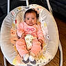 adorable, baby, baby_seat, bouncer, child, couch, floral_pattern, furniture, harness, indoor, infant, living_room, onesie, pink_clothing, portrait, sitting, socks, toy, wide_eyes, wood_floor