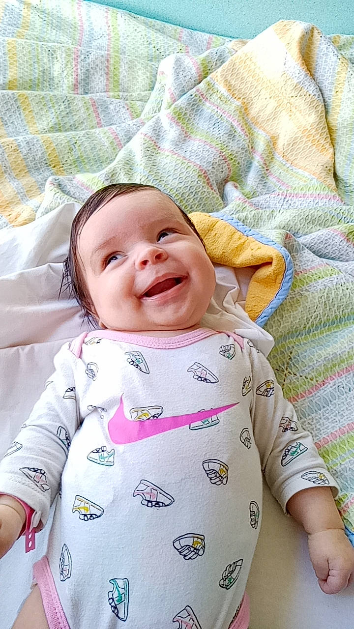 Melya participe au concours pour gagner de l'argent avec cette photo : baby, baby_laughing, baby_toddler_clothing, cheek, child, comfort, face, facial_expression, grass, happy, linens, magenta, pattern, person, pink, product, skin, sleeve, smile, textile