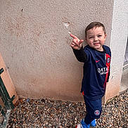 Loïs participe au concours pour gagner de l'argent avec cette photo : ball, blue_clothing, boy, casual, child, football, footwear, gate, gravel, outdoor, playful, pointing, portrait, psg, red, smiling, soccer, sportswear, wall, white