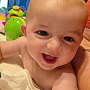 Austin is registered to the contest to win money with this photo: arm, baby, blanket, cheerful, child, closeup, cute, expression, eyes, face, happy, head, indoor, infant, mouth, person, playtime, skin, smiling, toy