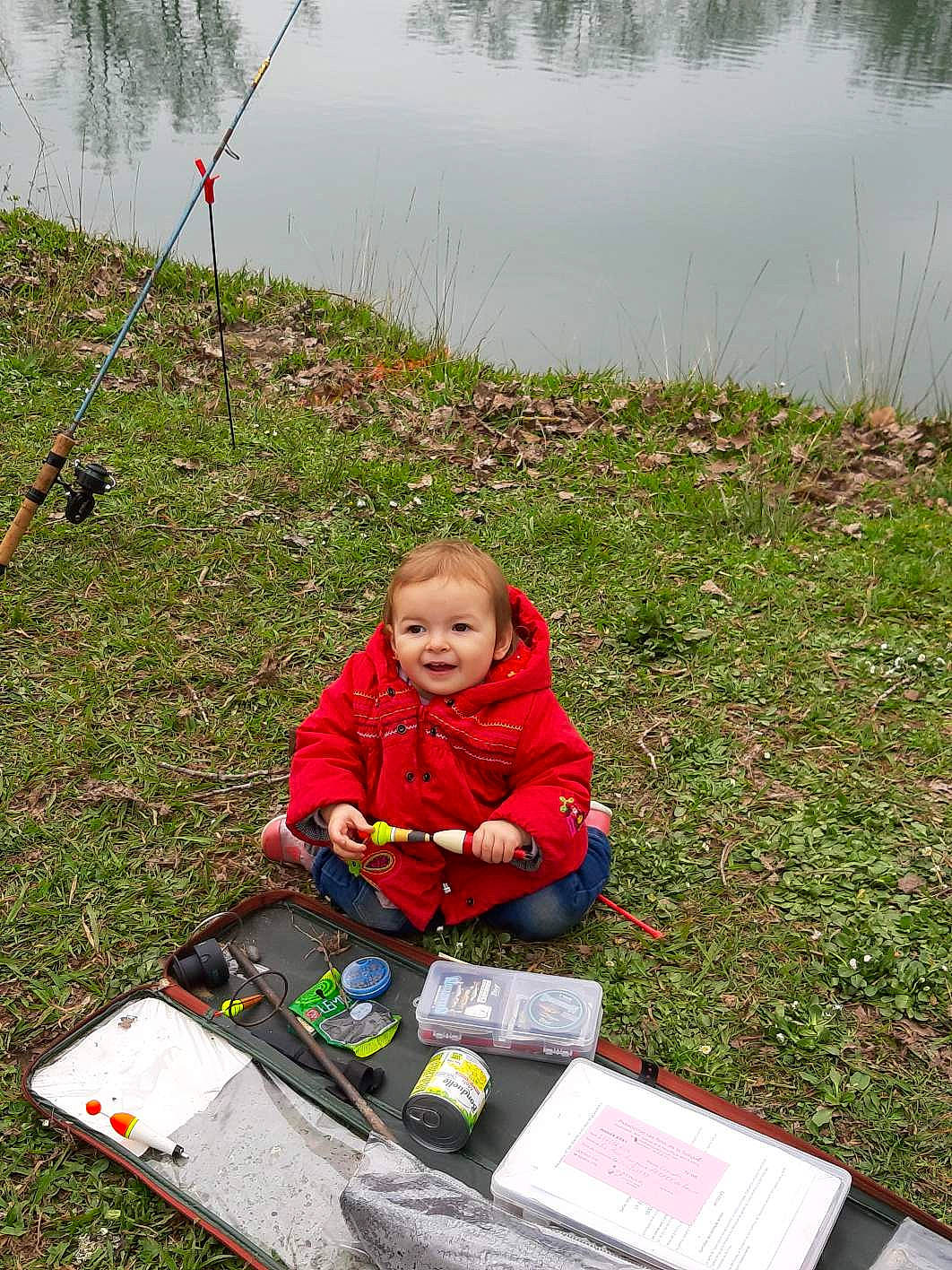 Léana participe au concours pour gagner de l'argent avec cette photo : child, flag, fun, grass, grassland, hoodie, jacket, joy, lake, lawn, leisure, outdoor_recreation, people_in_nature, person, plant, play, recreation, sitting, soil, toddler