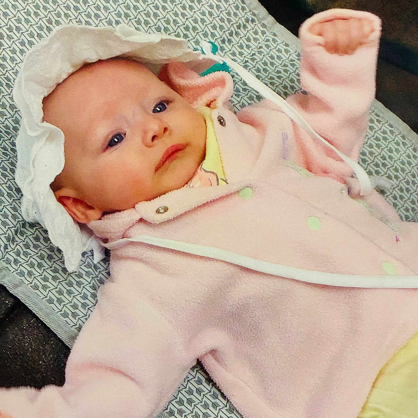 Harlie is registered to the contest to win money with this photo: baby, infant, child, portrait, lying_down, pink_outfit, onesie, hat, mittens, blanket, cushion, patterned_fabric, face, eyes, indoor, cozy, newborn, relaxed, photography, cute