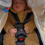 Jakel is registered to the contest to win money with this photo: baby, sleeping, car_seat, fuzzy_suit, child, toddler, safety_harness, cute, cozy, infant, clothing, hands, face, closed_eyes, transport, seatbelt, soft_texture, adorable, indoor, resting