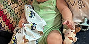 Kazdyn joined the competition — help win amazing prizes! baby, infant, blanket, plush_toy, cushion, crocheted_blanket, person, child, indoors, cute, soft_toy, green_clothing, barefoot, bracelet, carpet, relaxed, smile, portrait, comfort, home