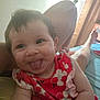 Brayleanna is registered to the contest to win money with this photo: arm, baby, bed, blanket, child, cute, face, floral_pattern, hair, happy, indoor, infant, legs, light, person, red_dress, relaxed, skin, smiling, tongue_out