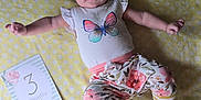 Brayleanna is registered to the contest to win money with this photo: age_card, baby, blanket, butterfly, card, child, cute, feet, floral_pants, hands, headband, indoors, infant, looking_at_camera, lying_down, polka_dot, portrait, shirt, smiling, soft_light