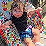 Brayleanna is registered to the contest to win money with this photo: arms, baby_seat, black_shirt, blue_shorts, casual, child, clothing, colorful, face, happy, legs, outdoor, pacifier, pattern, person, smiling, sunlight, toddler, white_socks, wooden_floor