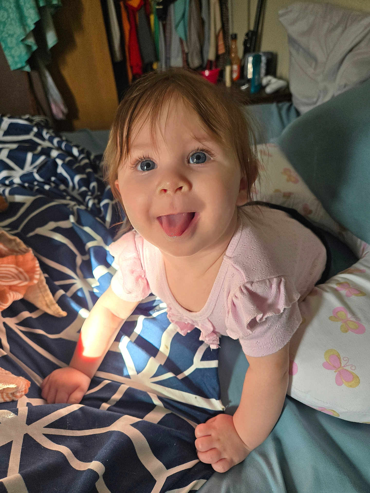 Brayleanna is registered to the contest to win money with this photo: baby, tongue_out, blue_eyes, crawling, blanket, pillow, bedroom, clothing, child, infant, cute, indoors, smiling, person, furniture, home, soft_lighting, young_child, pink_shirt, playful