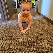 Brayleanna joined the competition — help win amazing prizes! toddler, child, crawling, carpet, indoor, yellow_shirt, hair_bun, fan, clothing, room, floor, person, baby, household_items, curious, young_child, carpeted_floor, portrait, casual, home