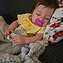 baby, pacifier, sleeping, blanket, yellow_onesie, duck_embroidery, couch, fleece_blanket, hand, face, infant, resting, peaceful, soft_texture, colorful, cozy, indoors, child, portrait, comfort