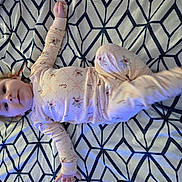 Brayleanna is registered to the contest to win money with this photo: baby, child, pajamas, bed, blanket, pattern, geometric_pattern, face, person, infant, sleepwear, cute, lying_down, indoors, young_child, smiling, happy, arms, legs, hair