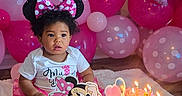 Miley is registered to the contest to win money with this photo: toddler, birthday, cake, candles, balloons, pink, minnie_mouse, birthday_party, child, celebration, polka_dots, headband, dress, floor, blanket, indoor, smile, party_decorations, happy, cute