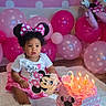 toddler, birthday, cake, candles, balloons, pink, minnie_mouse, birthday_party, child, celebration, polka_dots, headband, dress, floor, blanket, indoor, smile, party_decorations, happy, cute