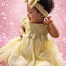 adorable, baby, celebration, child, crown, cute, face, fashion, festive, girl, glitter, happy, headband, person, pink_background, portrait, sitting, smiling, sparkles, yellow_dress