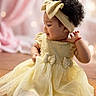 accessory, baby, child, curly_hair, cute, earrings, fashion, girl, happy, headband, indoor, pink_curtains, playful, portrait, sitting, smiling, soft_background, toddler, wooden_floor, yellow_dress