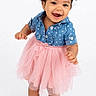 barefoot, blue_shirt, bows, child, curly_hair, cute, fashion, full_body, girl, happy, joyful, one_person, pink_tutu, portrait, smiling, standing, studio, toddler, white_background, young_child