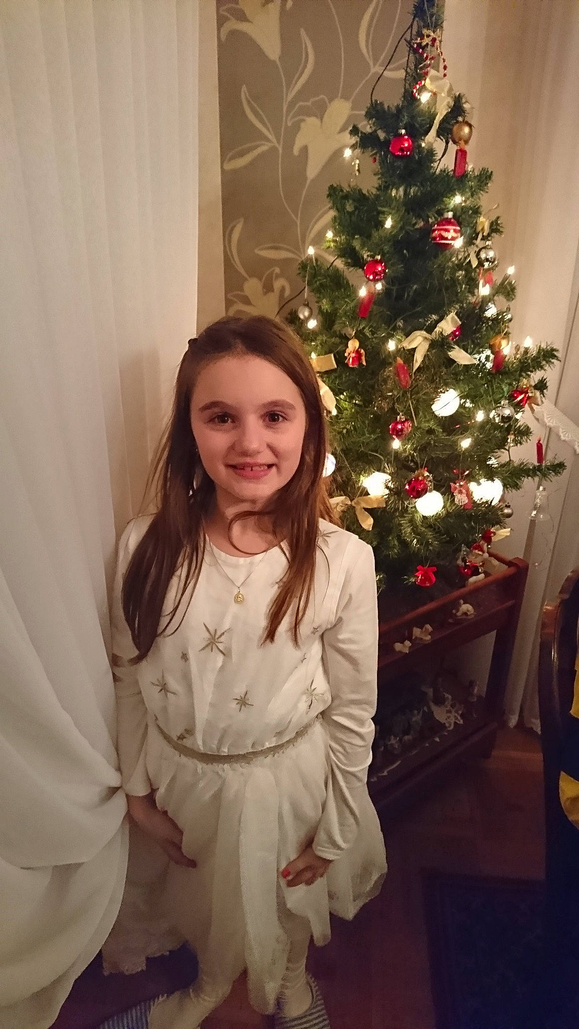 Chloé a rejoint le concours — aidez-le/la à gagner de superbes lots ! child, christmas, christmas_decoration, christmas_ornament, christmas_tree, costume, decor, dress, event, flower, fun, girl, holiday, joy, outerwear, person, skin, smile, standing, textile