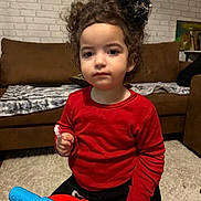 Razen participe au concours pour gagner de l'argent avec cette photo : bow, brick_wall, carpet, casual_clothing, child, couch, curly_hair, curly_hair_bow, expressionless, furniture, home, indoor, living_room, person, playtime, portrait, red_shirt, toddler, toy_vehicle, young_child