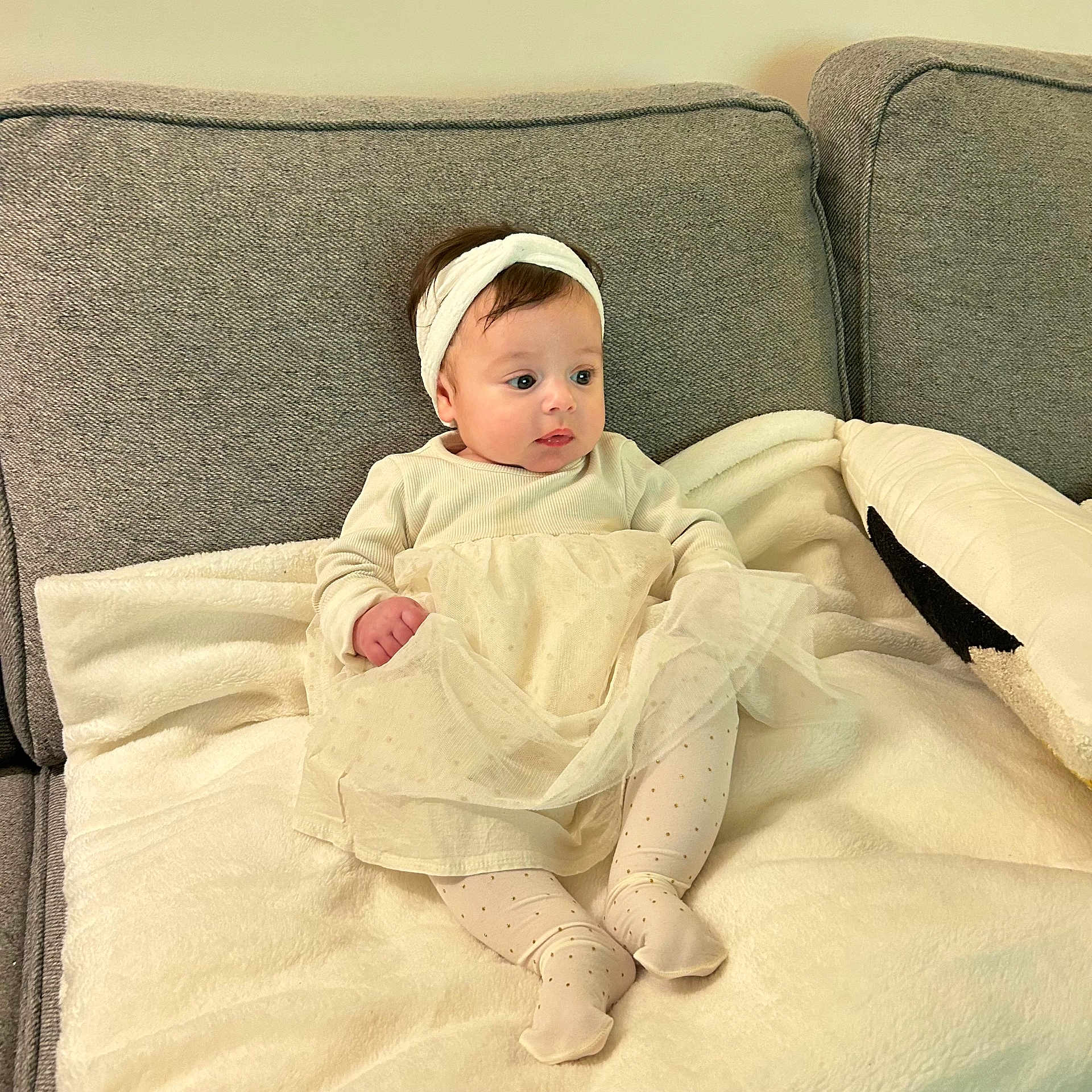 Avah participe au concours pour gagner de l'argent avec cette photo : baby, blanket, child, comfortable, couch, cozy, cute, dress, gray_couch, headband, home, indoors, infant, looking_away, portrait, relaxed, sitting, soft_texture, tights, warm_colors